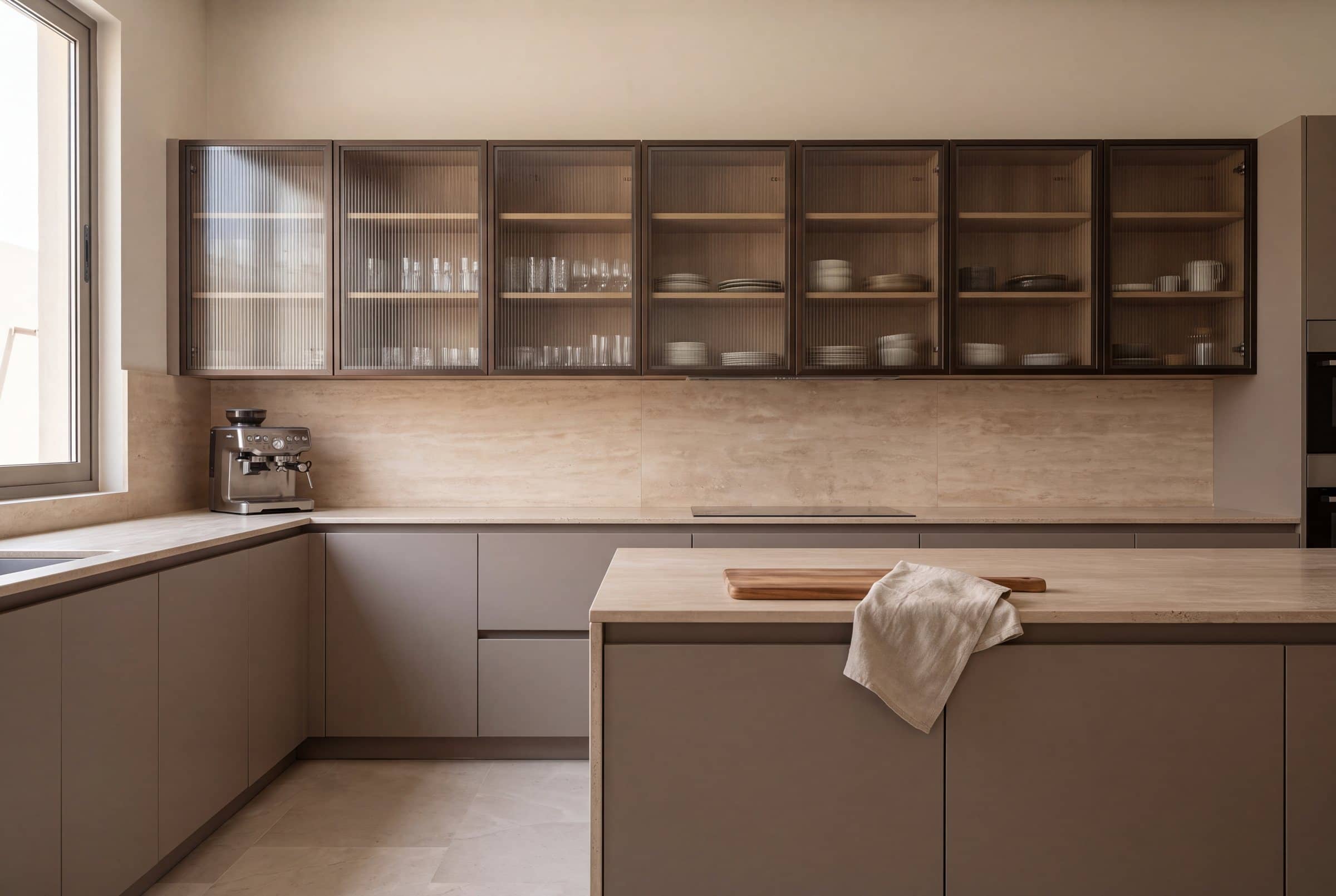 Kitchen with reeded-glass wall cabinets in dark bronze aluminium frames above stone-grey base units